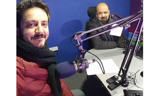 Massood Sanjer, left, smiles as his colleague, Humayoun Daneshyar, looks on inside a studio of Arman FM in Kabul. (Via Facebook)