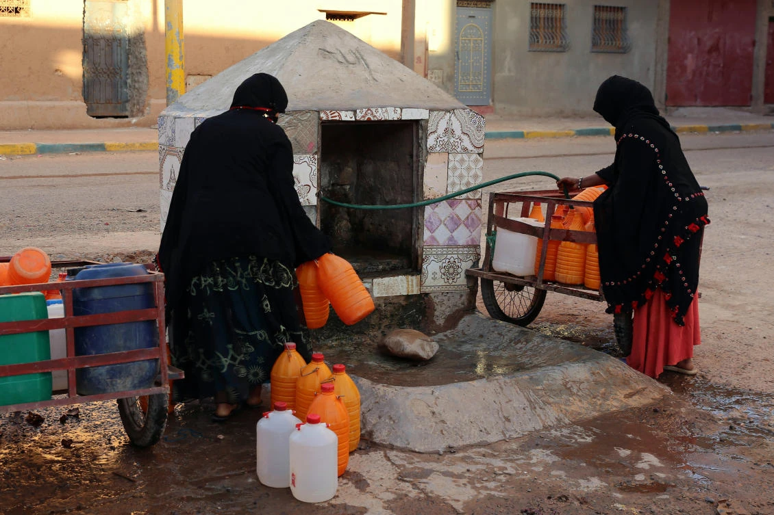 In this Oct. 19, 2017 file photo, Moroccan women filling up containers with water from a hose, in Zagora, southeastern Morocco. Experts blame poor choices in agriculture, growing populations and climate change for the water shortages in towns like Zagora, which has seen repeated protests for access to clean water in recent weeks. (AP Photo/Issam Oukhouya, File)