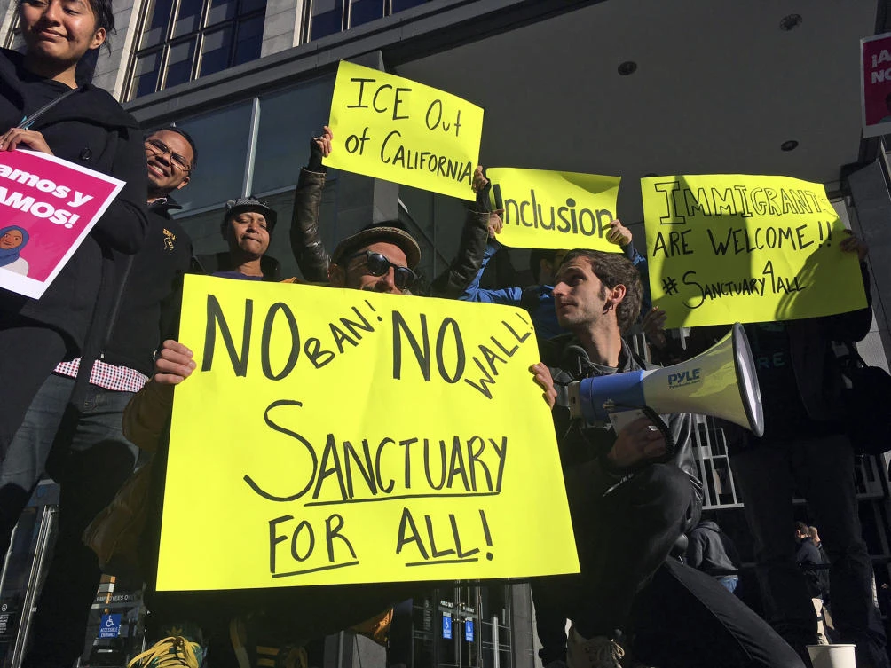 In this April 14, 2017, file photo, protesters hold up signs outside a courthouse where a federal judge was to hear arguments in the first lawsuit challenging President Donald Trump’s executive order to withhold funding from communities that limit cooperation with immigration authorities in San Francisco. (AP)