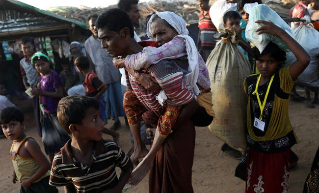 Rohingya refugee Suray Khatun, 70, is carried by her son Said-A-Lam, 38, as they enter Kutupalong refugee camp, near Cox's Bazar, Bangladesh a day after crossing the Myanmar border, on November 20, 2017. (REUTERS/Susana Vera)