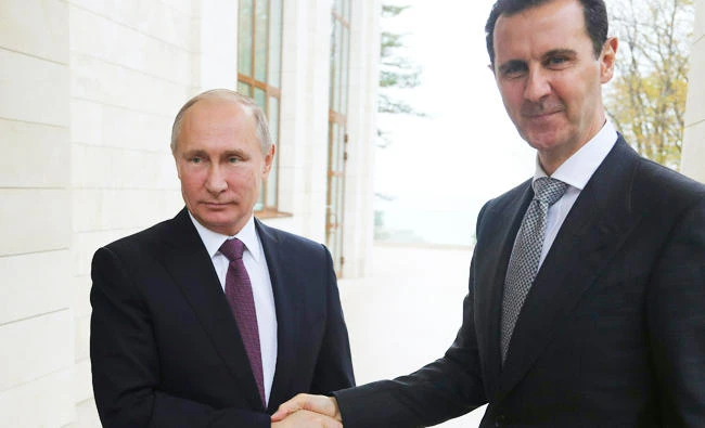 Russia's President Vladimir Putin (L) shakes hands with his Syrian counterpart Bashar al-Assad during a meeting in Sochi on November 20, 2017. / AFP / SPUTNIK / Mikhail KLIMENTYEV
