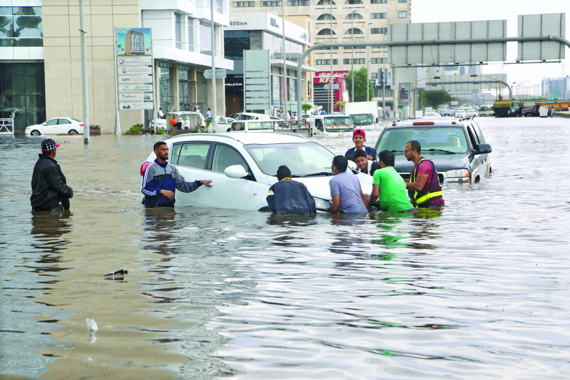 Volunteers try to remove a car from a flooded street in Jeddah after Tuesday’s downpour. (AN photo by Salman Marzouki)