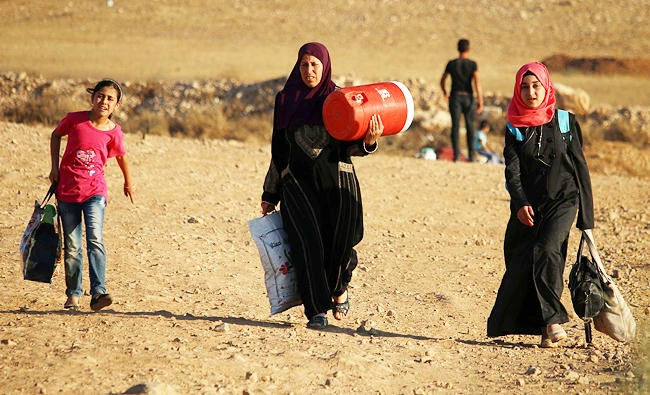 Syrian refugees carry belongings as they return to Syria after crossing the Jordanian border near the town of Nasib, in the southern province of Daraa, in this August 29, 2017 photo. (AFP)