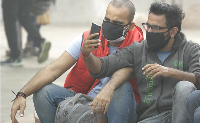 In this Thursday, Nov. 9, 2017, photo, Indian men in New Delhi take selfies as air pollution peaked this week, rising to more than 30 times the World Health Organization's recommended safe level. (AP Photo/Manish Swarup)