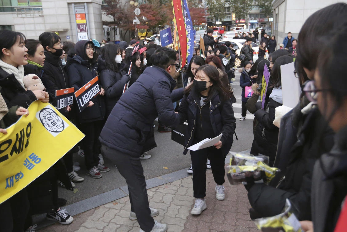 A teacher, center left, greets a student wishing her success in the college entrance exams in front of an exam hall in Seoul. More than 590,000 students are expected to take test, which stretches over nine hours. (AP)