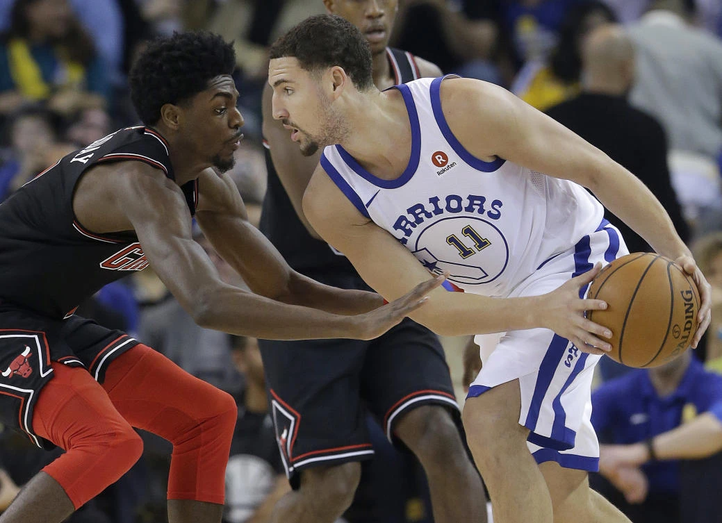 Golden State Warriors guard Klay Thompson is defended by Chicago Bulls guard Justin Holiday during the first half of an NBA basketball game in Oakland. (AP)