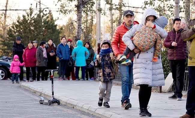 In this Nov. 24, 2017 photo, a woman carries a child as they arrive at the RYB kindergarten in Beijing, China. (AP)