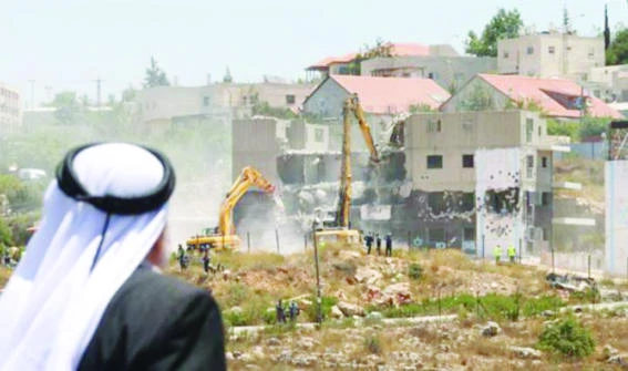 A Palestinian watches Israeli heavy machinery demolish apartment blocs in the occupied West Bank settlement of Beit El. (File photo/Reuters)