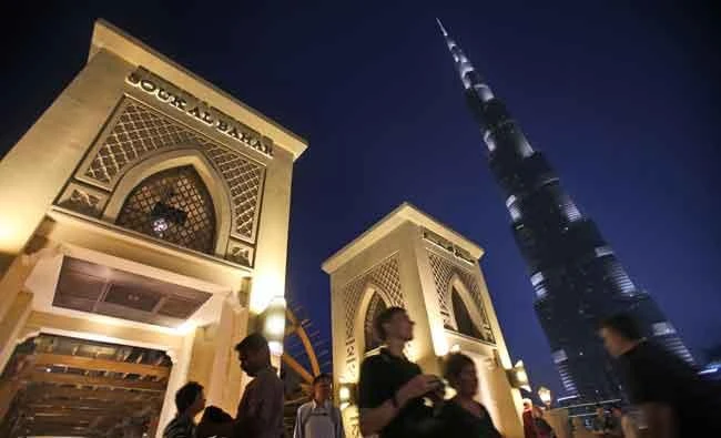 With the world tallest tower, Burj Khalifa, in background, tourists and visitors cross a bridge to Souk Al Bahar in Dubai, United Arab Emirates, Monday, April 13, 2015. If you’re visiting Dubai for a long stopover or business trip, make sure to leave a little space in your bag for a bathing suit, flip flops and souvenirs. (AP Photo/Kamran Jebreili)