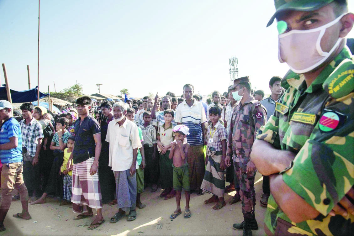 A Bangladeshi soldier stands before Rohingya refugees queueing for aid at the Kutupalong refugee camp in Cox’s Bazar on Sunday. (AFP)