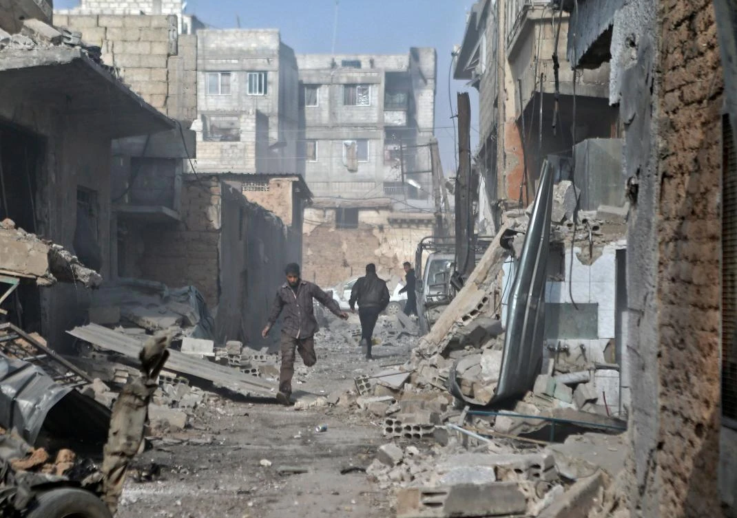 Syrian men run through an alley in the rebel-controlled town of Mesraba, in the eastern Ghouta region on the outskirts of the capital Damascus, on Nov. 27, 2017, following reported bombardment by government forces. (AFP/Abdulmonam Eassa)