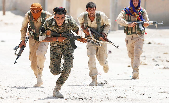 Kurdish fighters from the People's Protection Units (YPG) run across a street in Raqqa, Syria, in this July 3, 2017 photo. (REUTERS)
