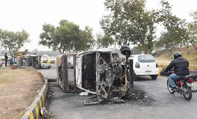 A Pakistani commuter rids past by a burnt police van after a protest of Tehreek-i-Labaik Yah Rasool Allah Pakistan (TLYRAP) religious group in Islamabad, in this October 28, 2017 photo. (AFP)
