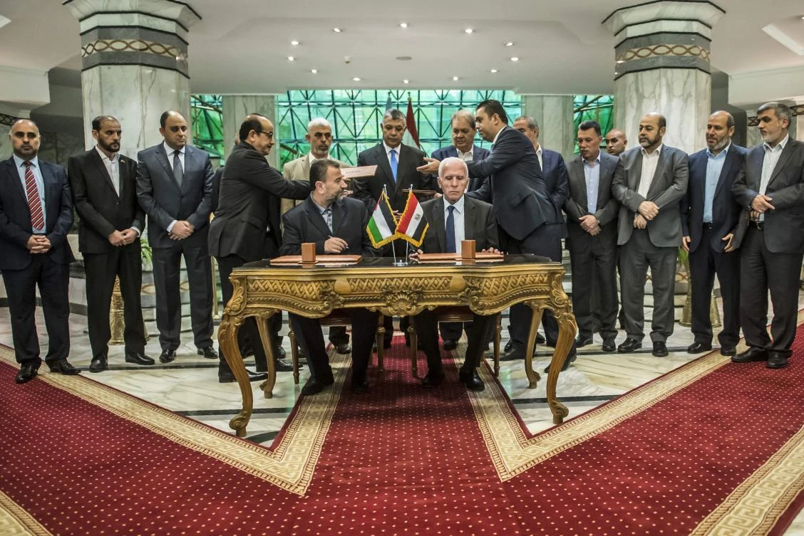 The moment the deal was reached: Hamas’s new deputy leader Salah Al-Aruri (seated L) and Fatah’s Azzam Al-Ahmad (seated R) sign a reconciliation deal in Cairo on Thursday, Oct. 12, 2017, as the two rival Palestinian movements ended their decade-long split following negotiations overseen by Egypt. (AFP/Khaled Desouki)