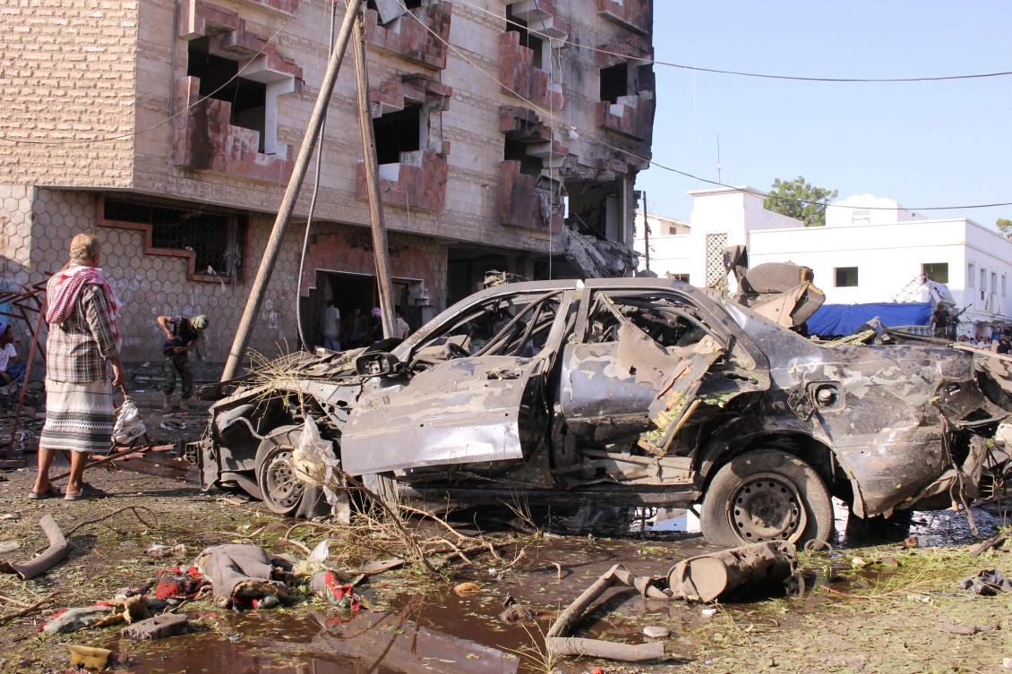 A man stands by a damaged car at the site of a car bomb attack outside the Finance Ministry offices in the southern port city of Aden, Yemen Nov. 29, 2017. (Reuters/Fawaz Salman)