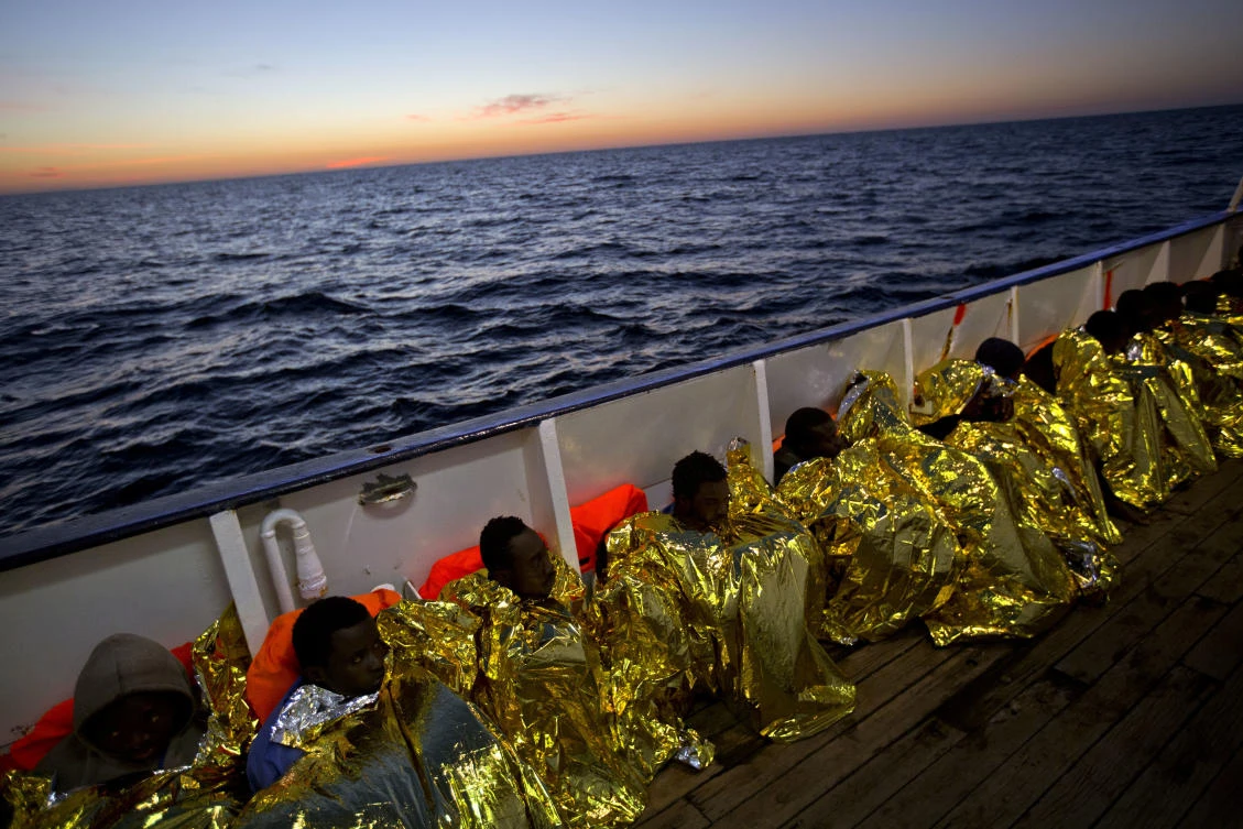Wrapped in blankets, Sub-Saharan migrants sit on the deck of a boat after their rescue in the Mediterranean sea, about 24 miles off the coast of Libya. (AP)