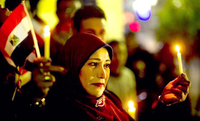 A woman holds candles and a national flag during a candlelight vigil for victims of a Friday mosque attack at the Journalists Syndicate, in Cairo, Egypt, on Monday. (AP)