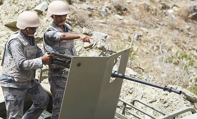 Saudi border guards talk as they stand on an armed military vehicle. (AFP)