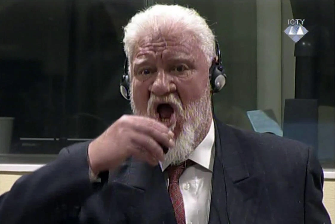 In this photo provided by the ICTY on Wednesday, Nov. 29, 2017, Slobodan Praljak brings a bottle to his lips, during a Yugoslav War Crimes Tribunal in The Hague, Netherlands. Praljak yelled, “I am not a war criminal” and appeared to drink from a small bottle, seconds after judges reconfirmed his 20-year prison sentence for involvement in a campaign to drive Muslims out of a would-be Bosnian Croat mini state in Bosnia in the early 1990s. (ICTY via AP)