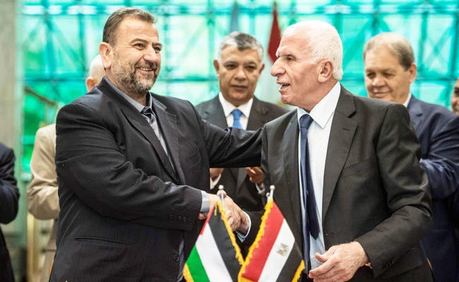 Fatah's Azzam Al-Ahmad, right, and Saleh Al-Aruri, left, of Hamas shake hands after signing a reconciliation deal in
Cairo in this file photo. (AFP)