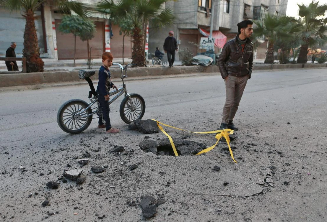A Syrian boy looks at a hole in the ground caused by an un-detonated rocket that fell following a reported air strike in the rebel-controlled town of Hamouria, in the eastern Ghouta region on the outskirts of the capital Damascus, on Nov. 23, 2017. (AFP/Abdulmonam Eassa)