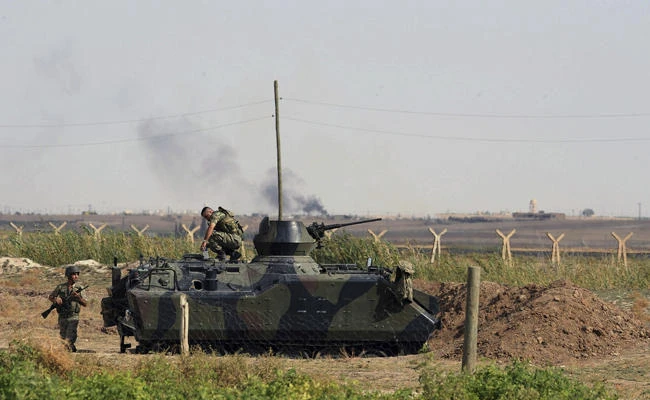 This Friday, Oct. 5, 2012 file photo, Turkish military take up positions on the Turkish side of the border near Syrian rebel-controlled town of Tel Abyad, in Akcakale, Turkey. Turkey on Friday said it is drafting a plan for naturalized Syrians to serve in the Turkish military. (AP Photo, File)