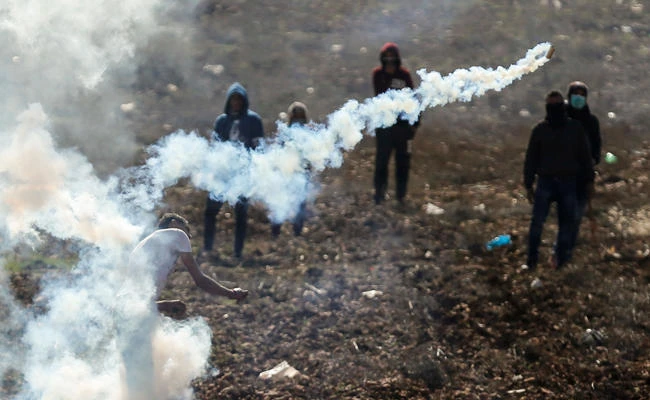 A Palestinian throws back a tear gas canister at Israeli soldiers during clashes in the northern village of Qusra in the occupied West Bank near Nablus on December 1, 2017. (AFP / ABBAS MOMANI)