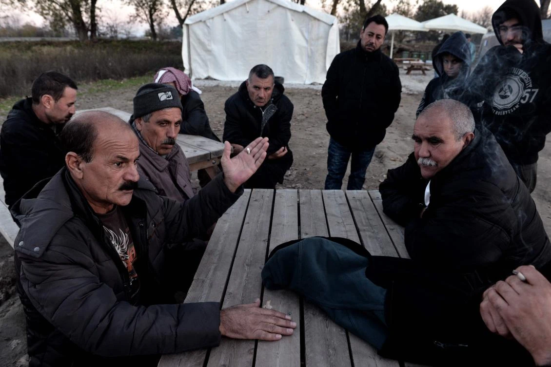 Yazidi refugees have a discussion as they sit outside at the Serres refugee camp, northern Greece, on November 24, 2017. (AFP)