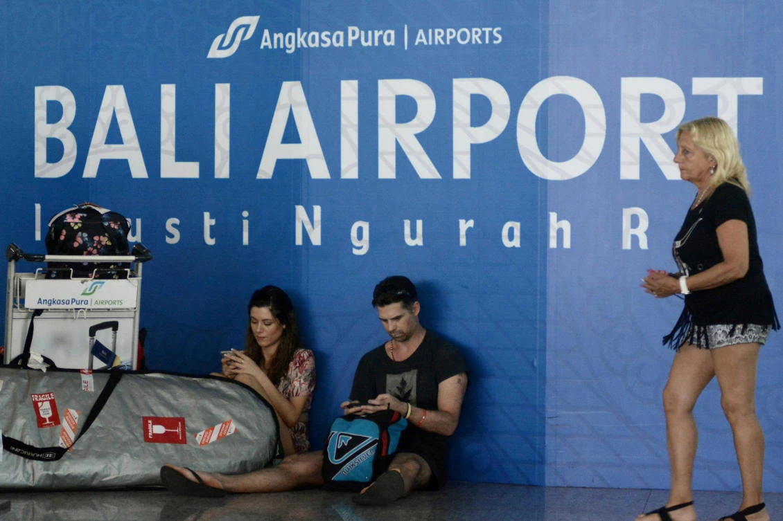 Tourists sit on a floor as wait for their flight at Ngurah Rai airport in Denpasar, Bali. Twenty flights were canceled on Friday evening due to concerns over ash. (Reuters)