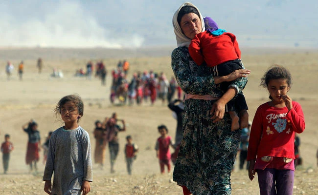 In this August 11, 2014 photo, Yazidis walk toward the Syrian border on the outskirts of Sinjar mountain to escape violence from Daesh terrorists. Daesh militants killed thousands of Yazidis in Sinjar and kidnapped thousands of women and girls from the community to abuse them as sex slaves. (REUTERS/Rodi Said/File Photo)