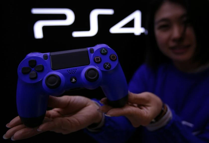 A staff at the PlayStation 4 launch event poses with PlayStation 4's game controller before its domestic launch event at the Sony Showroom in Tokyo February 21, 2014. (File photo by Reuters)