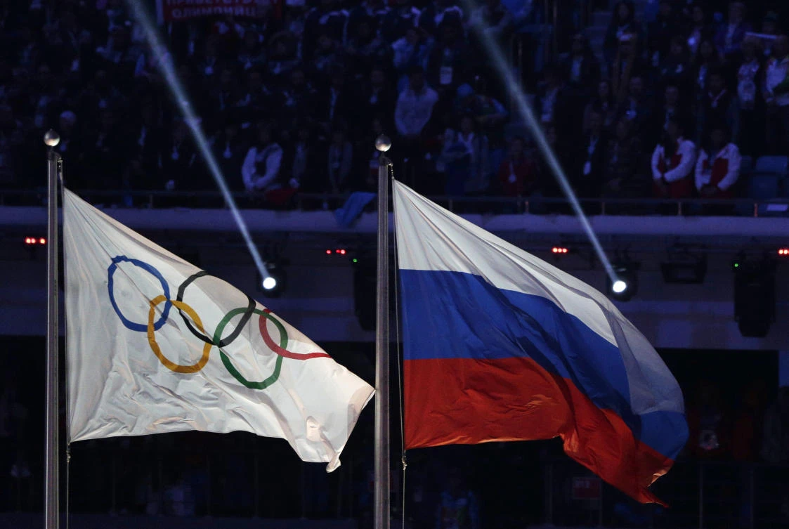 The Russian national flag, right, flies after next to the Olympic flag during the closing ceremony of the 2014 Winter Olympics in Sochi, Russia. Russia could be banned from competing at the Pyeongchang Olympics. The decision will come on Tuesday, Dec. 5, 2017 when the International Olympic Committee executive board meets in Lausanne, less than nine weeks before the games open on Feb. 9 in South Korea. (AP Photo/Matthias Schrader)