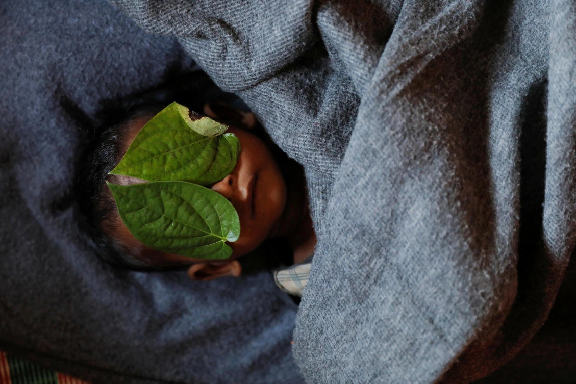 Leaves cover the face of 11-month-old Rohingya refugee Abdul Aziz, after his body was brought back to the family shelter, at the Balukhali refugee camp near Cox's Bazar, Bangladesh, a few hours after he died on December 4, 2017. (Reuters)