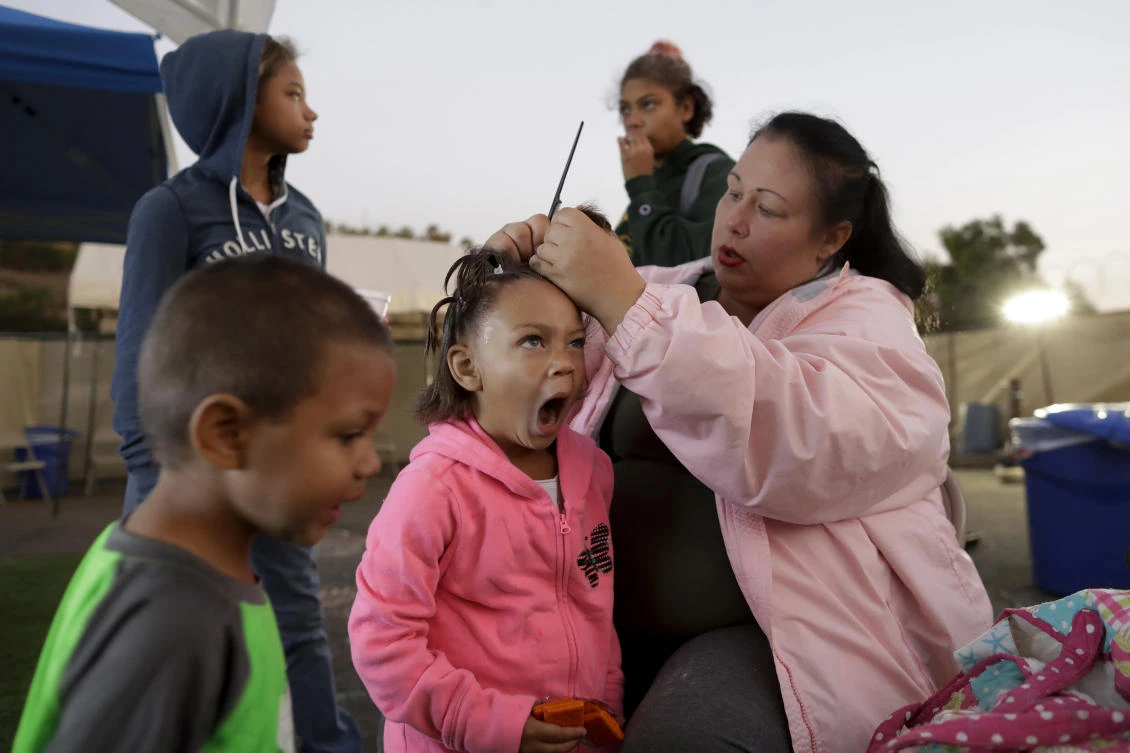 Christine Wade makes braids for Rayahna, 3, as Jaymason, 2, below left, Shawnni, 12, above left, and Shaccoya, 14, get ready to leave for school at dawn at the city-sanctioned tent encampment in San Diego. (AP)