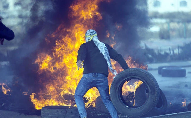 A Palestinian protester in the West Bank city of Ramallah burns tires on Thursday during clashes with Israeli troops following protests against US President Donald Trump’s decision to recognize Jerusalem as the capital of Israel. (AP)