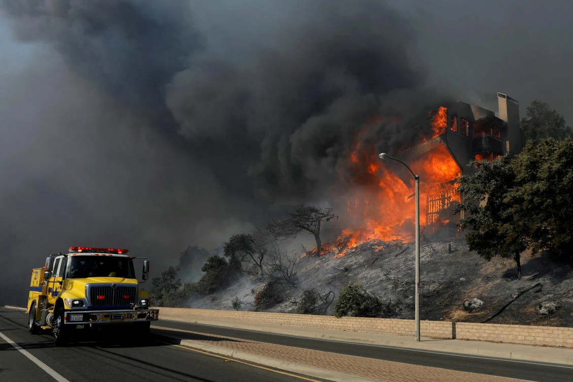 Above, a fire crew passes a burning home during a wind-driven wildfire in Ventura, California earlier this week. About 200,000 residents were evacuated from their homes at one point as the wildfires raged on. (Reuters)