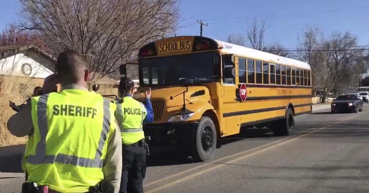 Police escort buses moving students and faculty from Aztec High School after a shooting incident on Thursday, December 7, in Aztec, New Mexico. (The Daily Times via AP)
