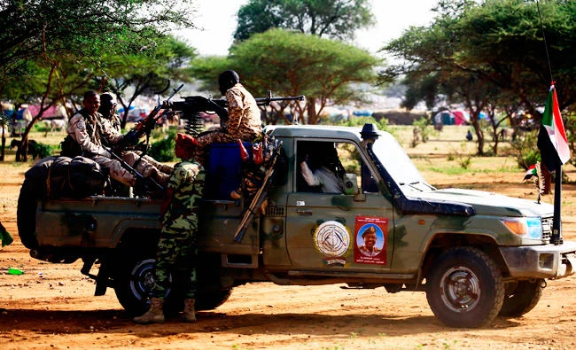 This file photo taken on September 23, 2017 shows Sudanese members of the Rapid Support Forces, a paramilitary force backed by the Sudanese government to fight rebels and guard the Sudan-Libya border, riding in the back of a pickup truck in the town of Umm al-Qura, northwest of Nyala in South Darfur province. (AFP)
