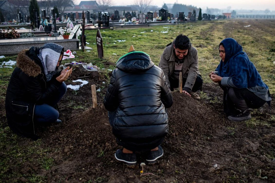 In this photograph taken on December 7, 2017, The Hussein family gather around the grave of six year-old Madina Hussein at a cemetery in the western Serbian town of Sid. Madina will never know London, the city her Afghan family hoped to reach. The six-year-old's body lies in a Serbian grave after she was struck by a train at the Balkan country's border. The Husseinis left Afghanistan around two years ago with the aim of reaching Britain, joining thousands of migrants still crossing the "Balkan route" towards western Europe, although it was officially shut down in early 2016. (AFP)