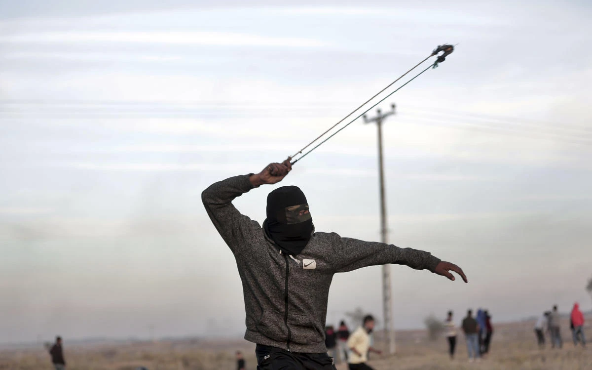 A Palestinian protester slings a stone towards Israeli soldiers during clashes on the Israeli border with Gaza, Saturday, Dec. 9, 2017. (AP)