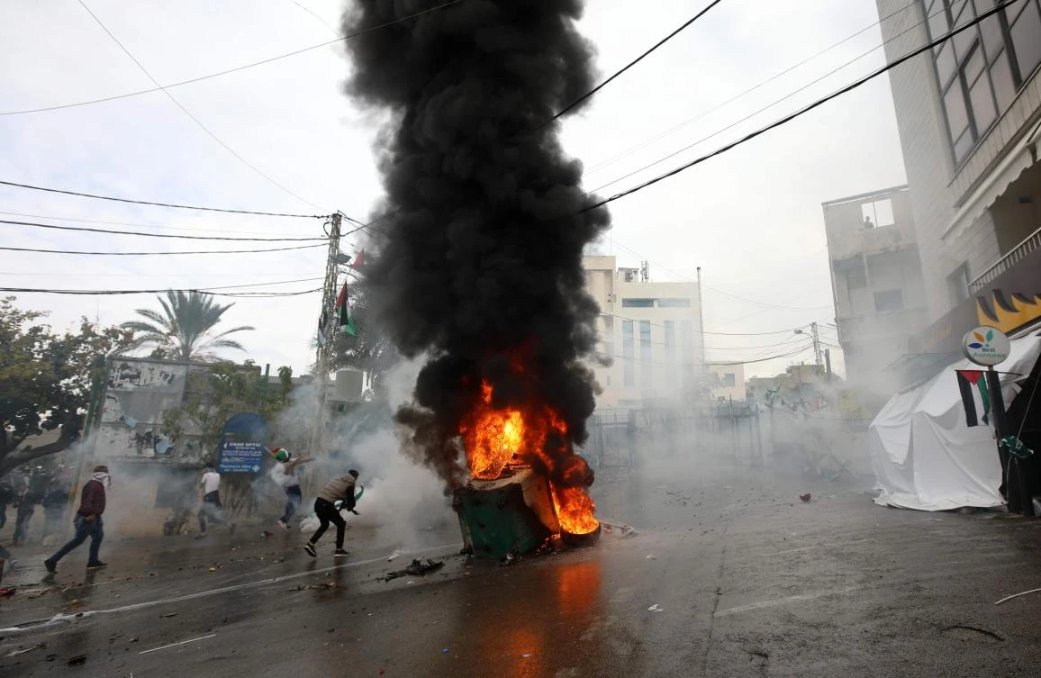 Lebanese security forces fire tear gas to disperse protestors as a fire burns in a dumpster during a demonstration outside the US embassy in Awkar, on the outskirts of the Lebanese capital Beirut, on December 10, 2017, to protest against Washington's decision to recognise Jerusalem as the capital of Israel. (AFP)