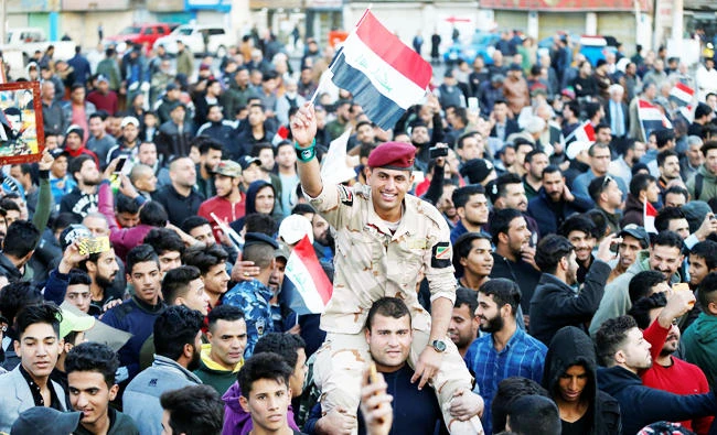 A member of Iraqi security forces carries an Iraqi flag as he celebrates the final victory over the Daesh at Tahrir Square in Baghdad, Iraq on Sunday. (REUTERS)