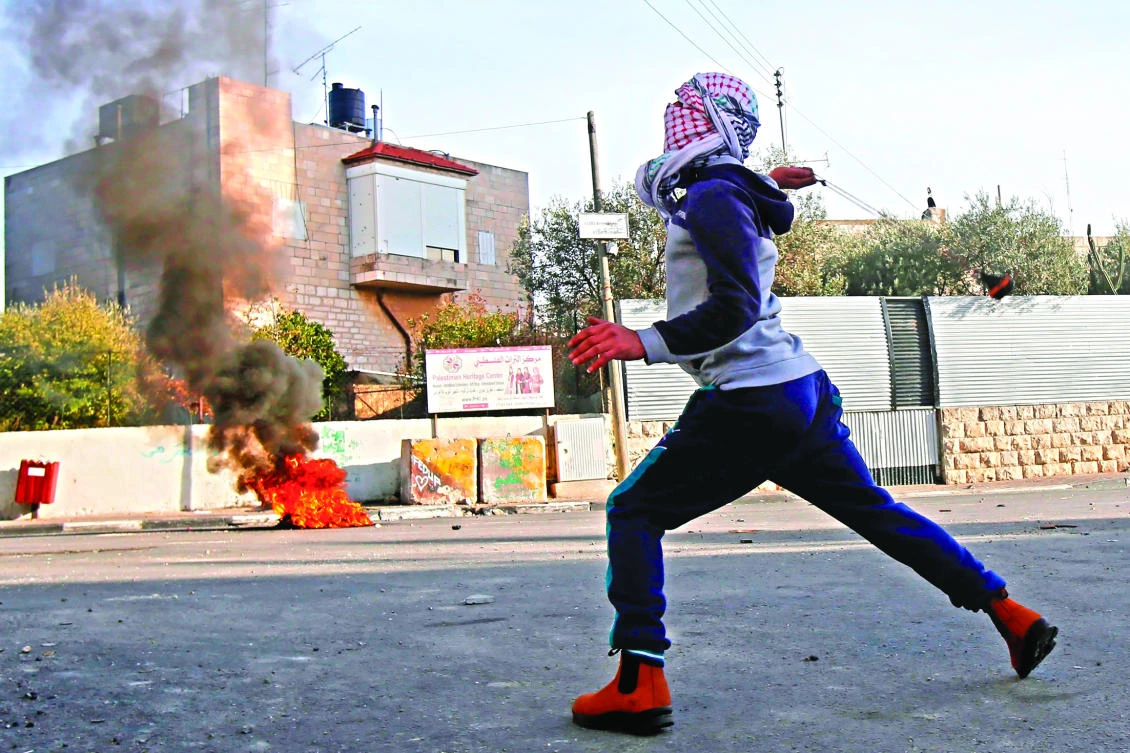 A Palestinian protester throws stones toward Israeli forces during clashes at the main entrance of the West Bank town of Bethlehem on Sunday. (AFP)