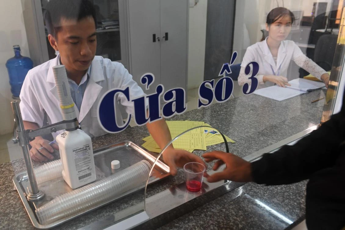 This picture taken on November 2, 2017 shows staff handing a dose of methadone to a recovering drug addict at a treatment clinic in the northern city of Bac Giang. During four years of compulsory rehab in Vietnam, Trung spent his drug-free days gluing together false eyelashes as part of what authorities billed as valuable 'work therapy' for his heroin addiction. But critics say the work of Trung and tens of thousands of others is tantamount to forced labour that rarely helps users extinguish their addiction. (AFP)