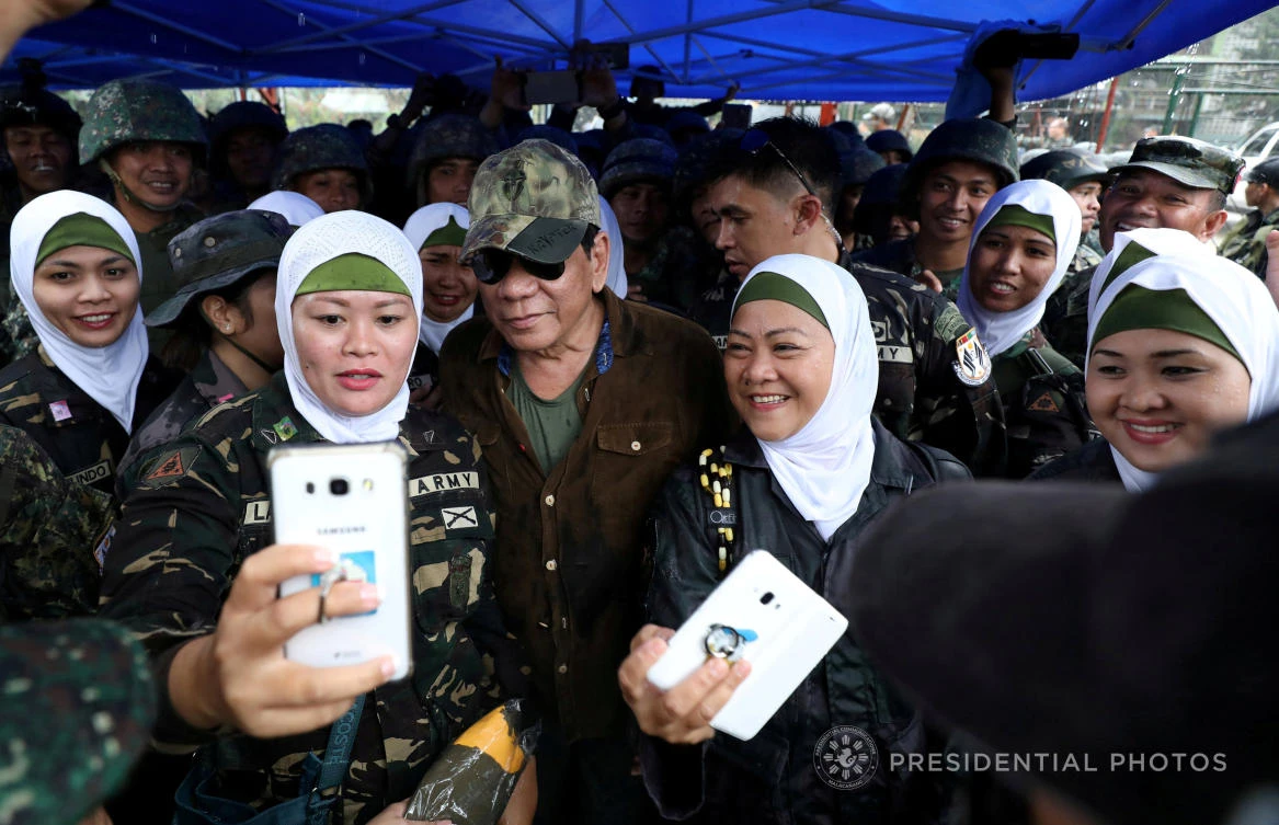 Philippine President Rodrigo Duterte poses for a picture with female soldiers during his visit at Bangolo town in Marawi city, southern Philippines October 17, 2017. (Reuters)