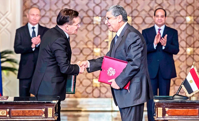 Egyptian president Abdel Fattah el-Sisi (back-R) and his Russian counterpart Vladimir Putin (back-L) applaud as Egypt's electricity and renewable energy minister, Mohamed Shaker (R), shakes hands with Alexei Likkhachev, the director general of Russia's Atomic Energy Corporation Rosatom, after signing a bilateral agreement in Cairo on Monday. (AFP)