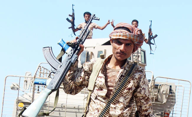A Yemeni fighter loyal to the Saudi-backed Yemeni president flashes his Kalashnikov assault rifle as he walks on a road leading to the town of Khokha which was retaken from Shiite-Huthi rebels, about 120 kilometres south of the Huthi rebel-held Red Sea port of Hodeida, on December 10, 2017. (AFP)