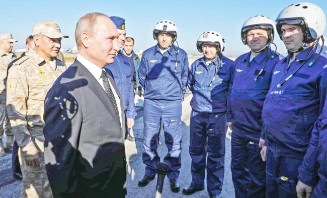 Russian President Vladimir Putin (2nd-L) and Russian Defence Minister Sergei Shoigu (L) meet with Russian air force pilots during their visit to the Russian air base in Hmeimim in the northwestern Syrian province of Latakia on December 11, 2017. (AFP)