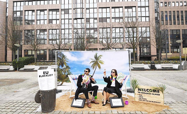 Oxfam activists stage a satirical street-play mimicking wealthy people hidding their money in tax haven, in this December 5, 2017 photo, near the European institutions in Brussels, within a meeting of European Union ministers over a credible blacklist of non-EU tax havens. (AFP)