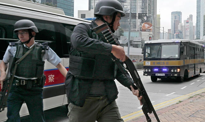 Police officers stand guard next to prison bus carrying British banker Rurik Jutting to the High Court in Hong Kong. (AP)